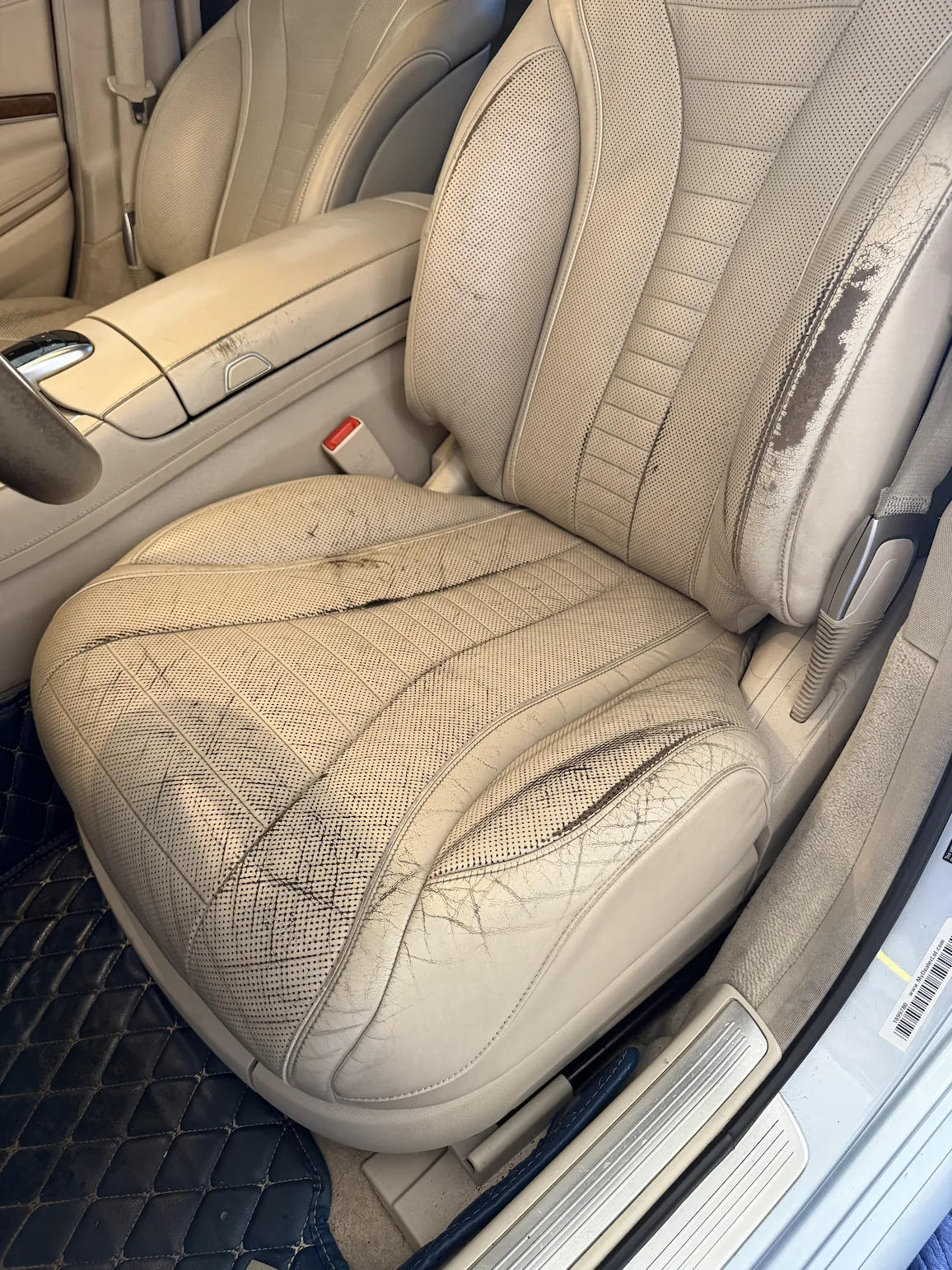 Cracked leather driver seat bolster before repair in Denver